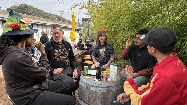 Five Clonetopia attendees gather around a wooden barrel table on an outdoor patio.